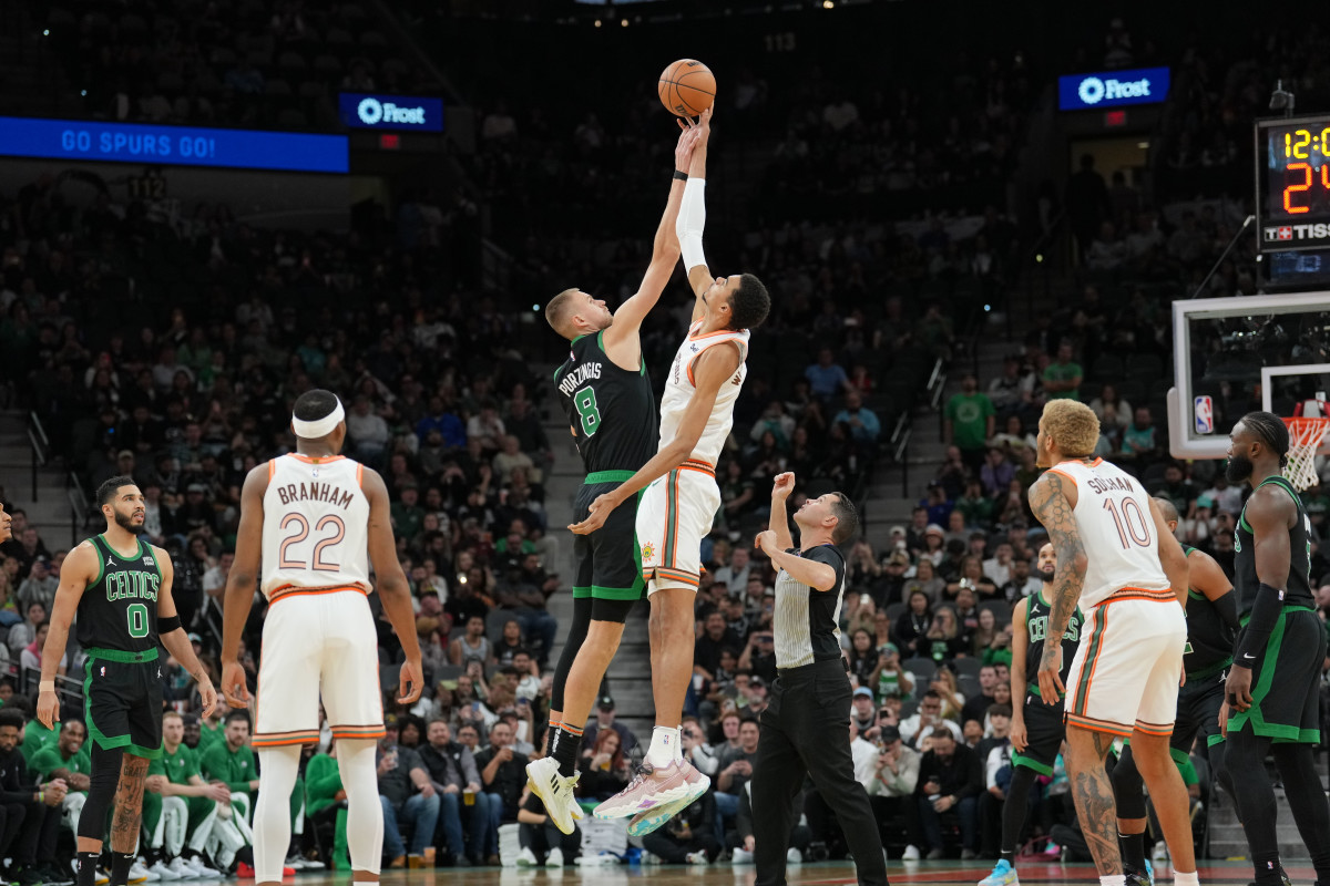 Dec 31, 2023; San Antonio, Texas, USA; Boston Celtics center Kristaps Porzingis (8) and San Antonio Spurs center Victor Wembanyama (1) go after the opening tip in the first half at Frost Bank Center.